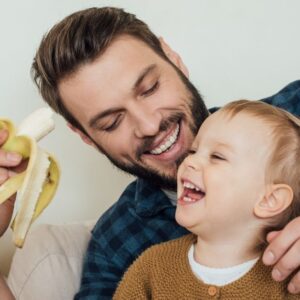 Dad feeding son banana
